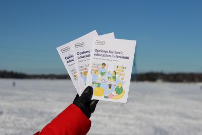 Hand holding brochures in front of a wintery scenery.