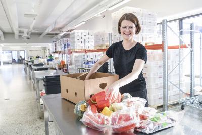 Stadin safkan johtaja Anni Heinälä pakkaamassa hävikkiruokaterminaalista ruokaa kuljetuslaatikoihin.