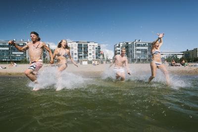 Aurinkolahden uimarannalla veteen juoksee kaksi naista ja yksi mies.