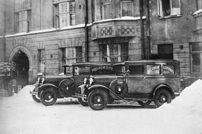 Kaksi vanhanaikaista autoa kuvassa, joka on otettu 1920-luvulla.