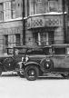 Kaksi vanhanaikaista autoa kuvassa, joka on otettu 1920-luvulla.